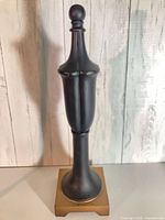 Full view of finial showing matte black body and antique brass base