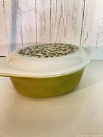 Side view of olive green casserole with white lid in place