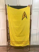 Full view of yellow Star Trek beach towel on rack showing insignia and border