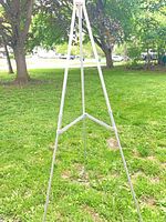 Full view of silver tripod easel standing on lawn