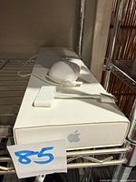 Mouse, adapters and closed Apple box on shelf