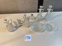 Group shot of all clear pressed glass items: four cruets with stoppers, two shakers, two bowls, two loose stoppers