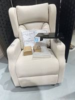 Front view of beige power lift recliner with accessories on seat