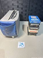 Projector case beside stacked 8-tracks
