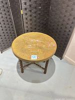 Full view of circular brass top side table with wooden twist leg base