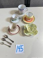 Overview of five teacup and saucer sets with three spoons