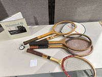 Group shot of three Wilson wooden rackets, Meylan stopwatch and Muhammad Ali book