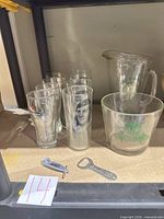 Group of glassware, pitcher, bowl and openers on shelf