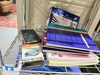 Shelf view showing notebooks, Faber-Castell book, OK Stand package, calculator, loose-leaf paper