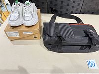 Sneakers on box beside messenger bag showing both items
