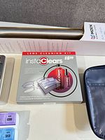 Close-up of instaClears lens cleaning kit and Moen grab bar package