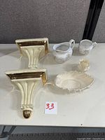 All six porcelain items laid out: two corbels, shell bowl, small shell vase, two creamers