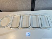 Five glass baking dishes lined up: four rectangular, one round