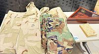 Overall lot with jackets, pants, flag case, book visible
