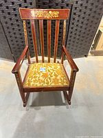 Front view showing carved floral crest, slat back, upholstery and gold accents