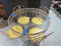 Full view of round glass-top table with four chairs and cushions