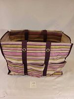 Front view of striped canvas tote showing exterior pockets and grommeted straps