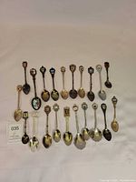Group shot of all souvenir spoons laid out showing quantity, variety of crests and overall condition