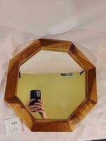 Front view showing octagonal shape, natural wood frame, and reflective surface