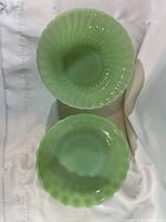 Top view of both jadeite bowls showing color, scalloped rim and fluted interior