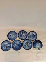 eight blue and white scenic porcelain plates displayed in two rows