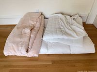 Folded feather duvet, mattress topper and cover on floor