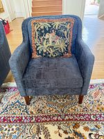 Front view of blue upholstered armchair with decorative cushion