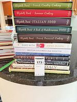 Tall stack of hardcover cookbooks showing spines and titles
