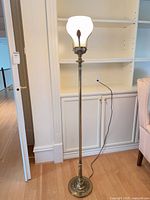 Full view of brass floor lamp lit, showing height and base