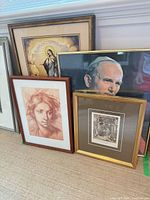 Four framed religious prints leaning against wall