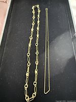 Overview of both gold tone chains on black tray