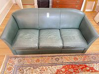 Front view of green leather couch with three cushions