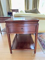 Full view of wood side table showing drawer, lower shelf, and overall form