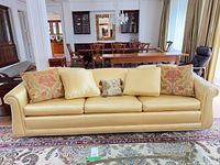 Full view of yellow satin sofa with five throw pillows in living room