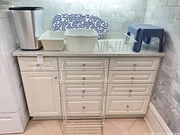 Full lot on countertop: stool, towel rack, ironing board, bins, dish drainer, trash bin