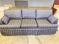 Front view of three-seat navy and gold patterned couch with two pillows