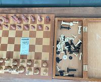 Board and storage compartment with wooden and plastic pieces visible