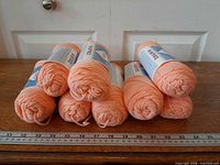 Eight skeins stacked, showing color, paper bands, ruler for scale