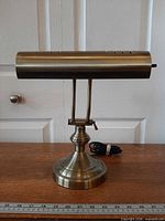 Front view of brass-tone banker’s desk lamp showing shade, arms, base and cord