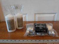 Full lot: 30-pack Tealites with two IKEA Fenomen pillar candles beside ruler for scale