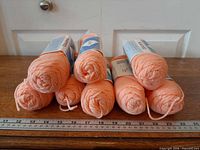 Eight light orange skeins stacked with ruler showing scale