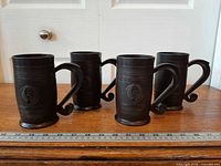 Four brown plastic KFC barrel mugs side by side with ruler for scale