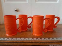 Group of four orange KFC barrel mugs on table