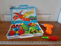 Open carry case showing toy screwdriver, manual screwdriver and assorted plastic construction pieces