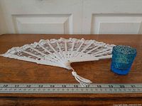 Fan fully opened and toothpick holder beside ruler for scale