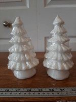 Front view of both white glitter Christmas tree candles beside ruler