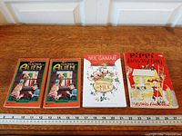 Front covers of all four books aligned with ruler for scale