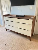 Front view of dresser showing six drawers, color contrast, legs, overall styling