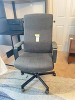 Front view of dark gray fabric office chair showing high back, armrests and wheeled base