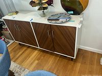 Front view of sideboard showing white top, brown veneer doors, black legs